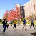 The women's Track and Field team runs behind Wood Hall in autumn.