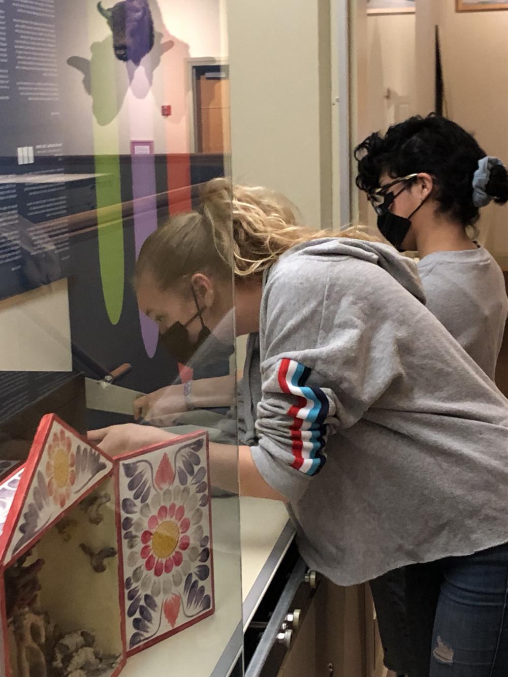 Tiffany Toledo and Dahlia Shearer set up their objects for an exhibit for Sylvia Lopez's class Health in the Spanish-speaking World.
